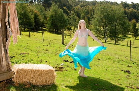 Plain looking blonde girl in glasses strips off blouse and skirt outdoors